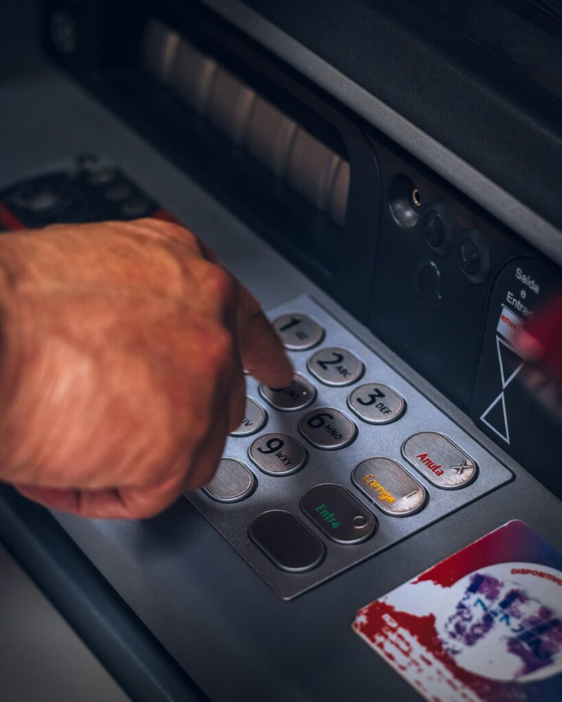 Hand pressing keypad of an ATM in Brazil, emphasizing modern banking technology.